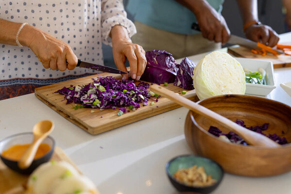 At home, Chopping vegetables, senior friends preparing meal together in kitchen. Cooking, friendship, healthy eating, lifestyle, culinary, meal preparation, unaltered — Stock Image Home Chopping Vegetables Senior Friends Preparing Meal Together Kitchen Cooking Stock Picture