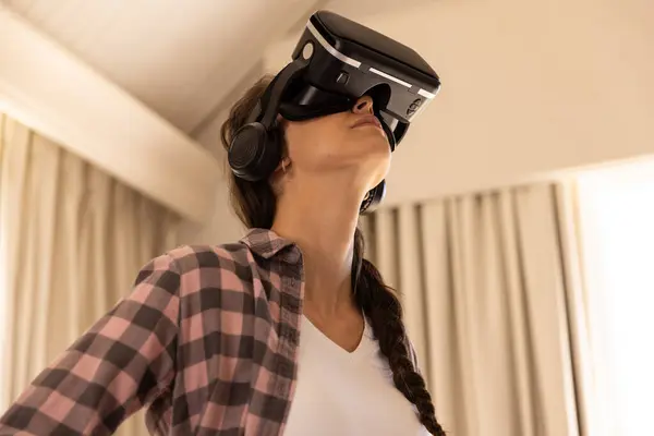 stock image Using VR headset, woman exploring virtual reality experience at home. Technology, immersive, gaming, futuristic, innovation, entertainment