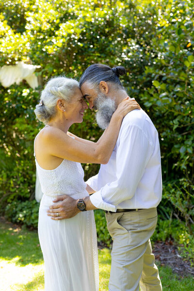 Senior bride and groom embracing and smiling in garden, at wedding. Love, elderly, togetherness, affection, happiness, retirement — Stock Image Senior Bride Groom Embracing Smiling Garden Wedding Love Elderly Togetherness Royalty Free Stock Photos