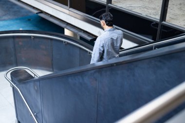 Walking down modern office staircase, man in business attire heading to work, copy space. professional, corporate, businessman, career, urban, lifestyle clipart