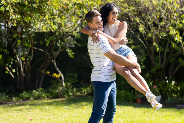 Man lifting and spinning woman in garden, both laughing and enjoying moment, copy space. Romance, couple, happiness, outdoors, love, embrace — Stock Image Man Lifting Spinning Woman Garden Both Laughing Enjoying Moment Copy Royalty Free Stock Photos