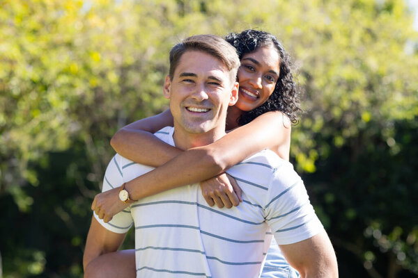 Smiling young couple enjoying piggyback ride outdoors in sunny park. Romance, happiness, playful, sunlight, love, carefree — Stock Image Smiling Young Couple Enjoying Piggyback Ride Outdoors Sunny Park Romance Stock Image