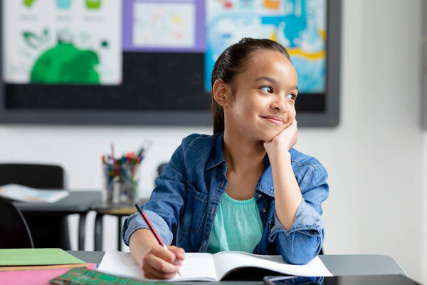Happy Biracial Schoolgirl Sitting Desk Class Looking Away Smiling Copy Stock Image