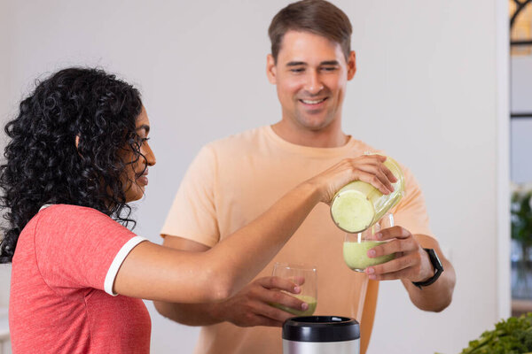 Pouring green smoothie into glasses, young couple enjoying healthy drink together. wellness, nutrition, lifestyle, fresh, detox, breakfast — Stock Image Pouring Green Smoothie Glasses Young Couple Enjoying Healthy Drink Together Stock Image