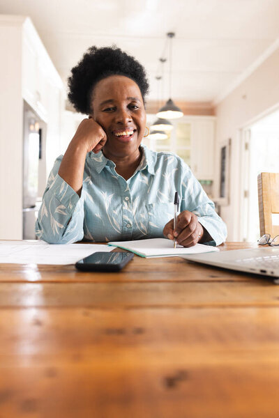 Portrait of happy senior african american woman with documents on table using laptop at home. Domestic life, retirement, technology and lifestyle, unaltered. — Stock Image Portrait Happy Senior African American Woman Documents Table Using Laptop Stock Photo