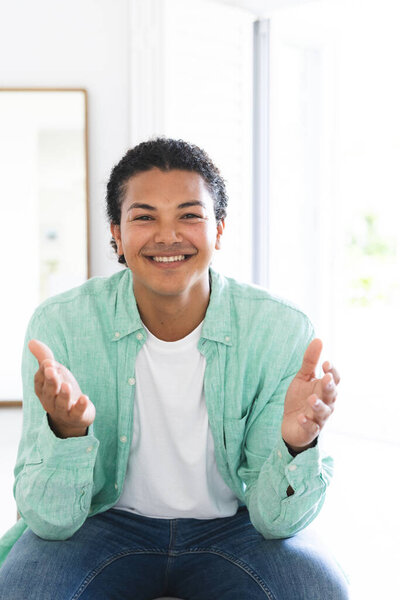 Young biracial man smiles warmly during a video call in a bright home setting. His casual attire suggests a relaxed and comfortable atmosphere indoors. — Stock Image Young Biracial Man Smiles Warmly Video Call Bright Home Setting Royalty Free Stock Photos