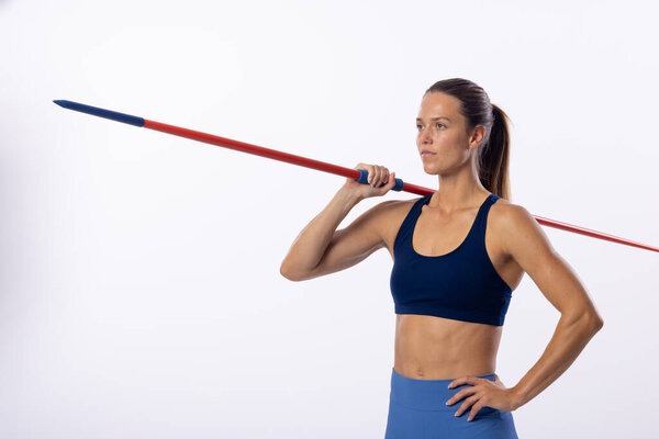 Young Caucasian female athlete holds a javelin on her shoulders, with copy space on a white background. She's in athletic wear, showcasing strength and focus in a studio setting. — Stock Image Young Caucasian Female Athlete Holds Javelin Her Shoulders Copy Space Royalty Free Stock Images