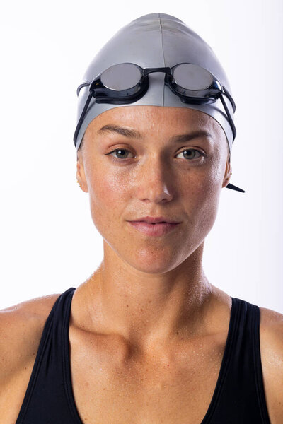 Young Caucasian female swimmer in swimwear poses confidently on a white background. Her swim cap and goggles suggest she's a professional swimmer ready for competition. — Stock Image Young Caucasian Female Swimmer Swimwear Poses Confidently White Background Her Stock Image