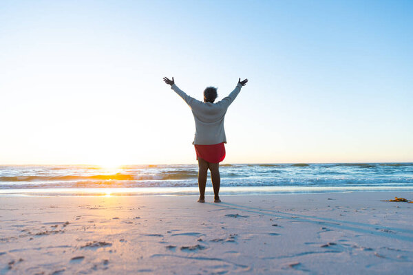 A senior African American woman enjoys a serene beach sunrise, with copy space. She stands on the sand embracing the new day with open arms. — Stock Image Senior African American Woman Enjoys Serene Beach Sunrise Copy Space Stock Image
