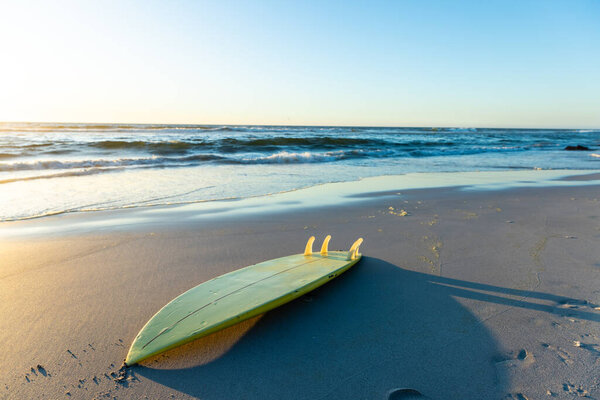 A surfboard rests on the sandy beach at sunset, with copy space. Outdoor leisure activities like surfing are popular for relaxation and sport. — Stock Image Surfboard Rests Sandy Beach Sunset Copy Space Outdoor Leisure Activities Stock Picture