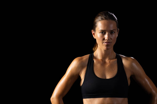 Young Caucasian female athlete poses confidently in sportswear on a black background, with copy space. Her determined expression and athletic build emphasize a fitness-focused lifestyle. — Stock Image Young Caucasian Female Athlete Poses Confidently Sportswear Black Background Copy Stock Image