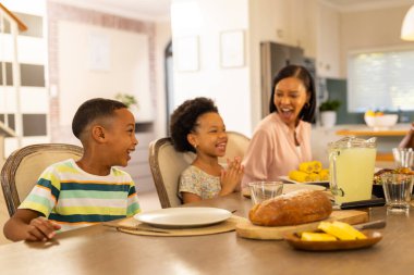 Smiling multigenerational family enjoying meal together at dining table with lemonade and bread. togetherness, happiness, bonding, gathering clipart