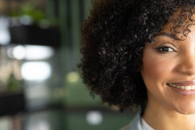 Smiling woman with curly hair in business setting, close-up portrait, copy space. professional, confidence, office, entrepreneur, executive, success clipart