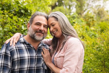 Happy mature couple embracing outdoors, enjoying nature and smiling warmly together. happiness, affection, relationship, love, connection, lifestyle clipart