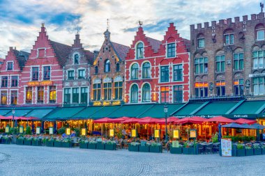 Geleneksel Flaman Barok binaları renkli cepheleri ve pazar meydanında gün batımında sokak restoranları, Bruges, Belçika