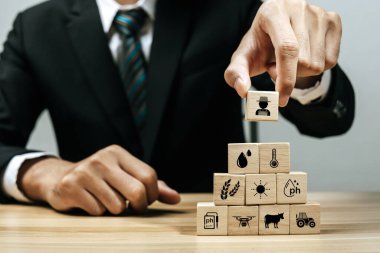 İşadamı yatırımcı el düzenlemesi ahşap blok ile masa üzerinde tarım ikonu, işletme yönetimi, takım lideri, tarım yeniliği, tarım endüstrisi, pazar eğilimi, iş kurma kavramı