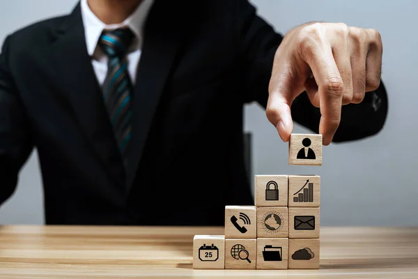 businessman investor hand arranging wood block with business finance icon on desk, business strategy business management, team leader, company growth, market trend, finance, business start up concept