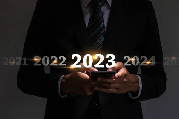 2022年から2023年への変化 事業計画と幸せな新年のコンセプトに暗い背景に仮想画面を持つ携帯電話を使用してスマートビジネスマンの投資家 — ストック写真