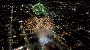 Şehir merkezindeki havai fişeklerden gelen büyük parlak ışıklar. Gece şehri Almaty 'deki bir İHA' nın hava görüntüsü, renkli ışıklar ve fenerler. İnsanlar dinleniyor. Arabalar geliyor. Şehirde bir tatil.