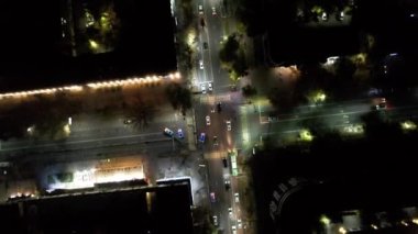 Gece kavşağındaki bir İHA 'nın hava görüntüsü. Otomobil ve otobüs trafiği yol boyunca ilerliyor. Fenerler parlıyor. Geçit polis arabaları tarafından yanıp sönen ışıklarla kapatıldı.