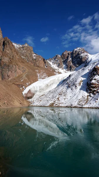 一个绿水的高山湖像镜子一样反射着冰川 你可以看到高山的最高峰 湖水已部分结冰 有些地方有大石头和大雪 莫兰湖 — 图库照片