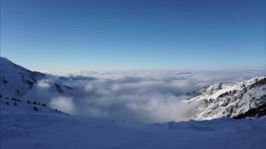 Kış dağlarında bulut ve sisten oluşan destansı bir okyanus. Büyük, güçlü beyaz bulutların ve dağlardaki berrak gökyüzünün zamanı. Kar var, kozalaklı ağaçlar yamaçlarda yetişiyor. Bulutlar dalgalar halinde gelir