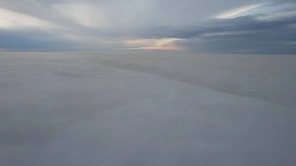 A heavenly ocean of clouds. Flying on a drone. The light yellow rays of the sun at sunset are reflected on the surface of the clouds. Double layer of clouds and heavy fog. Evening. Kazakhstan