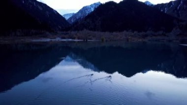 Ördekler aynalı pürüzsüz bir dağ gölünde yüzerler. Suda iz bırakırlar. Suyun yüzeyi gökyüzünü, günbatımını, bulutları ve dağları yansıtır. Ördekler İHA 'dan yüzerek uzaklaşır. Issyk