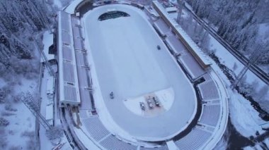 Dağlarda kış Alp Paten Pisti Medeo. Karlı ormanın ve dağların drone görüntüsü. Beyaz bulutlar ve sis vadide. Kar temizleme işlemi başladı. Büyük bir stadyum. Almaty, Kazakistan
