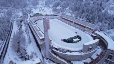 Dağlarda kış Alp Paten Pisti Medeo. Karlı ormanın ve dağların drone görüntüsü. Beyaz bulutlar ve sis vadide. Kar temizleme işlemi başladı. Büyük bir stadyum. Almaty, Kazakistan