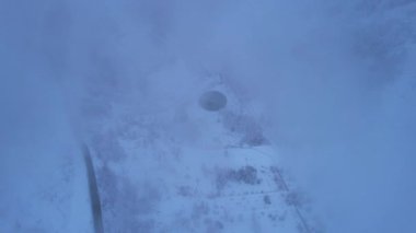 Dağlarda kış Alp Paten Pisti Medeo. Karlı ormanın ve dağların drone görüntüsü. Beyaz bulutlar ve sis vadide. Kar temizleme işlemi başladı. Büyük bir stadyum. Almaty, Kazakistan