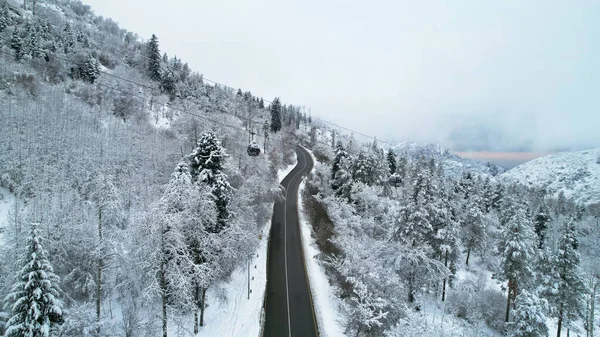 山里的缆车在冬天的森林里 小木屋沿着贡多拉公路穿过冬季的雪地和大雾 白云笼罩着群山 从无人机上俯瞰 阿拉木图Medeo — 图库照片