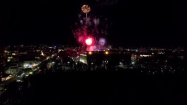 Şehir merkezindeki havai fişeklerden gelen büyük parlak ışıklar. Gece şehri Almaty 'deki bir İHA' nın hava görüntüsü, renkli ışıklar ve fenerler. İnsanlar dinleniyor. Arabalar geliyor. Şehirde bir tatil.