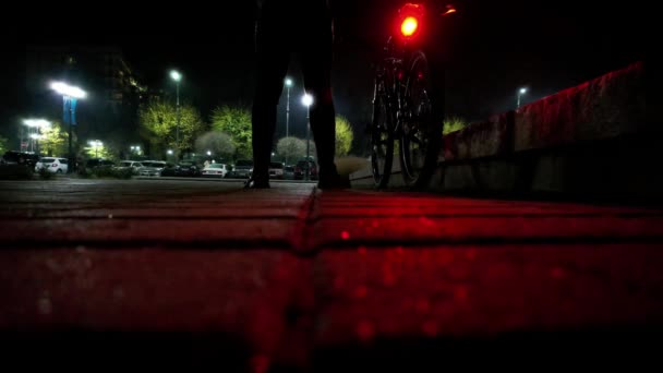 一个骑自行车的人站在那里观看夜市 地面上有一块瓷砖 反射着淡红色和绿色的灯笼 无人机起飞时看到了公园和房屋 阿拉木图市 — 图库视频影像
