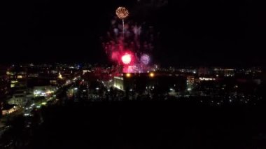 Şehir merkezindeki havai fişeklerden gelen büyük parlak ışıklar. Gece şehri Almaty 'deki bir İHA' nın hava görüntüsü, renkli ışıklar ve fenerler. İnsanlar dinleniyor. Arabalar geliyor. Şehirde bir tatil.