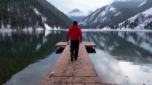 Guy Walks Pier Mountain Lake Dark Water Mirror Reflects Snowy — Stock Video
