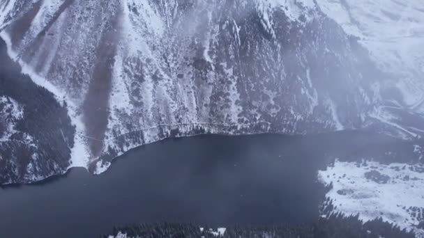 山の湖コルサイ上の雲の中に飛んでいます 雪の山や森のトップビュー 暗い湖の水 白い雲が浮かんでいる 峡谷の急な崖 カザフスタンの自然 アルマトイ — ストック動画