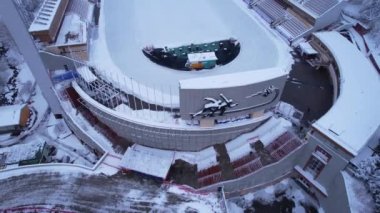 Dağlarda kış Alp Paten Pisti Medeo. Karlı ormanın ve dağların drone görüntüsü. Beyaz bulutlar ve sis vadide. Kar temizleme işlemi başladı. Büyük bir stadyum. Almaty, Kazakistan