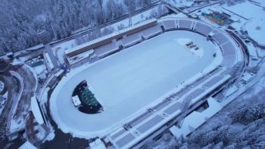 Dağlarda kış Alp Paten Pisti Medeo. Karlı ormanın ve dağların drone görüntüsü. Beyaz bulutlar ve sis vadide. Kar temizleme işlemi başladı. Büyük bir stadyum. Almaty, Kazakistan
