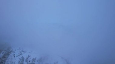 Bulutlarda kozalaklı ağaçlarla kaplı karlı dağlar. Medeo Barajı. Her şey sis ve karda. Noel ve yeni yıl geldi. Yoldaki, barajdaki ve ağaçlardaki insansız hava aracı görüntüsü. Almaty, Kazakistan