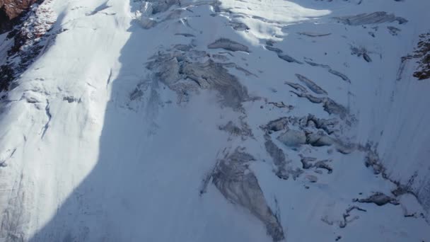 山中的一座古老的雪冰川 从空中俯瞰着覆盖着积雪的陡峭悬崖 被冰川覆盖的高峰 在有些地方有大石头 痕迹是可见的 — 图库视频影像