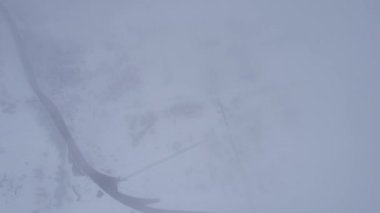 Bulutlarda kozalaklı ağaçlarla kaplı karlı dağlar. Medeo Barajı. Her şey sis ve karda. Noel ve yeni yıl geldi. Yoldaki, barajdaki ve ağaçlardaki insansız hava aracı görüntüsü. Almaty, Kazakistan