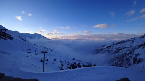 冬の山の中で雲と霧の壮大な海 白い雲の中の夕日のゴンドラ道のタイムラプス 人々はスノーボードやスキーです シンブラクアルマトイカザフスタン — ストック動画