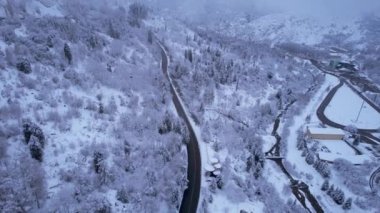 Kış ormanlarındaki dağlarda kablo tv arabası. Kulübeler, kar ormanları ve sis boyunca gondol yolu boyunca ilerliyorlar. Dağları beyaz bulutlar kapladı. İHA 'nın üst görüntüsü. Medeo, Almaty