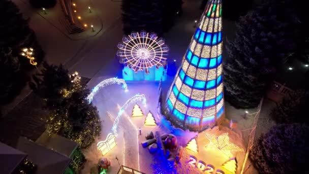明亮的圣诞装饰与圣诞树 圣诞树上放着花环和霓虹灯玩具 圣诞和新年的装饰 雪要下了人们拍照 无人机俯瞰 — 图库视频影像