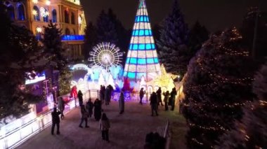 Noel ve yeni yıl için çok güzel dekore edilmiş bir ev. Kar yağıyor, Noel ağaçlarındaki çelenkler parlıyor, bir atlıkarınca, çeşitli dekorasyonlar, toplar ve oyuncaklar. İnsanlar yürüyor. Üst Manzara. Almaty