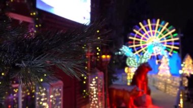 Kar altında yeni yıl ve Noel süslemeleri. Yumuşak kar taneleri düşüyor. Karda bir Noel ağacının kozalaklı dalları. Etraftaki her şey çelenk ve neon ışıkta parlıyor. Ayılar oturuyor.