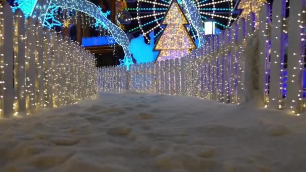 Светящийся Рождественский Переулок Гирляндах Снег Падает Украшено Неоновыми Огнями Забор — стоковое видео