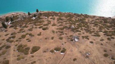 Dağlarda turkuaz mavi suyu olan bir göl. Temiz su, kozalaklı ağaçlar ve karlı dağlar. İnsanlar kıyı boyunca yürür, alçak çalılar büyür. Büyük Almaty Gölü. Kazakistan