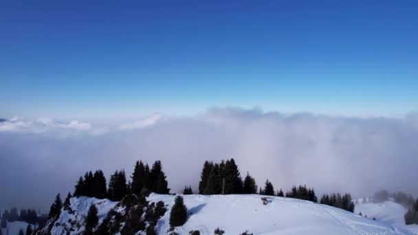 冬季雪山白积云 太阳的光芒落在部分云彩上 一个阴影从山顶升起 山上长着圣诞树 游客们在散步 — 图库视频影像